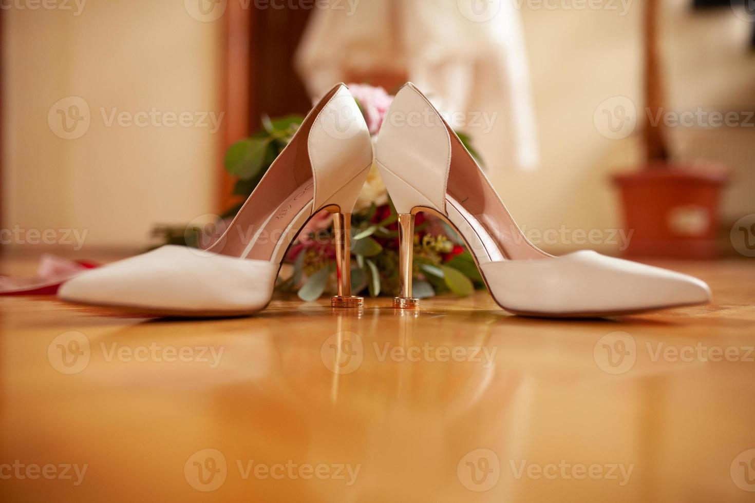 Wedding rings lie on white shoes. photo