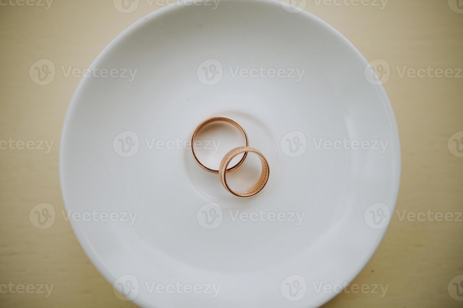 Golden wedding rings on white plate photo