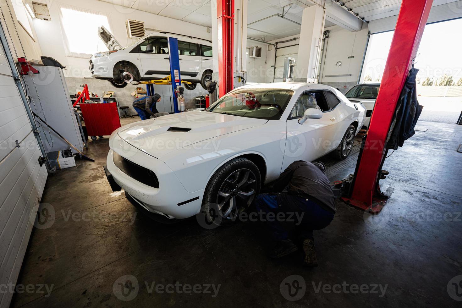 mecánico en Servicio reparar estación trabajando con músculo coche. hombre trabajador diagnosticar el chasis. foto