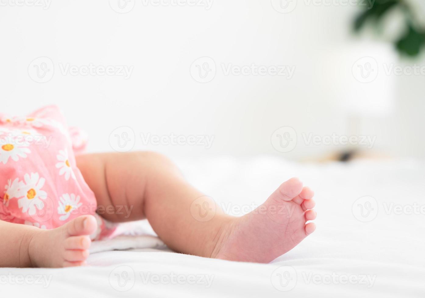 linda pequeño recién nacido bebé pies en cama a hogar foto