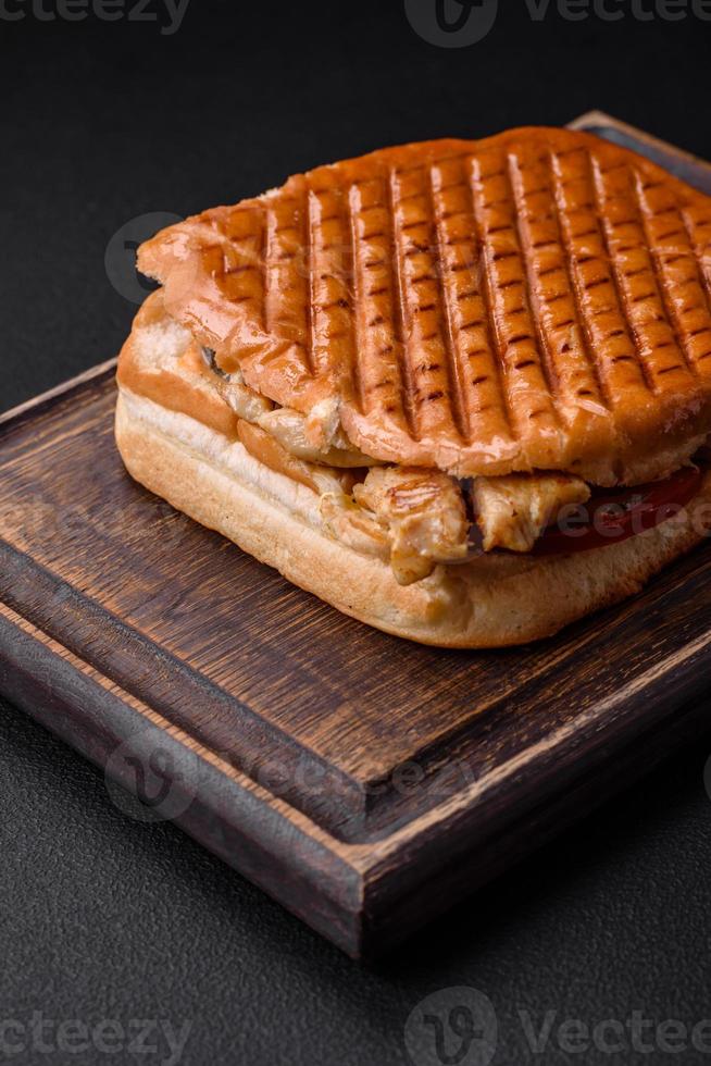 Delicious crispy sandwich with chicken breast, tomatoes, ketchup and spices photo