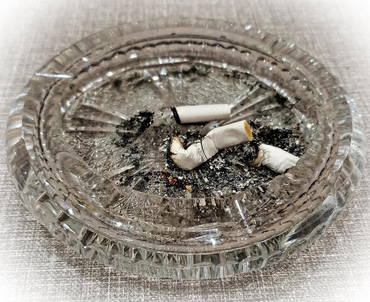 Cigarette butt in an ashtray on the table. The concept of the dangers of smoking. photo