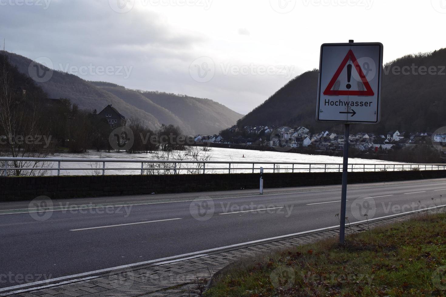 flood sign at the road next to the flood photo