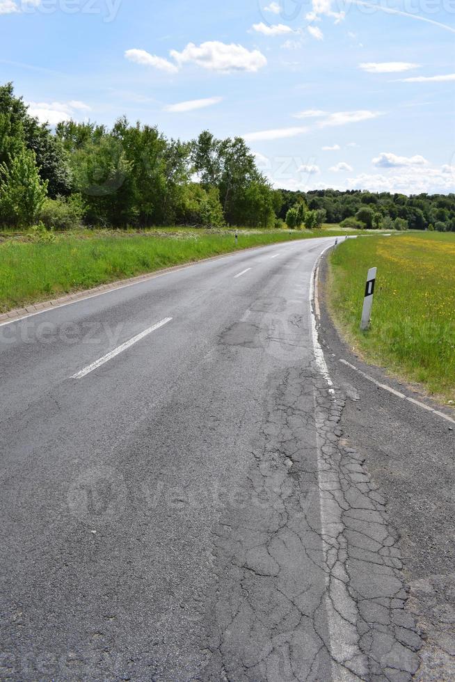 country road with bad cracks and green grass photo