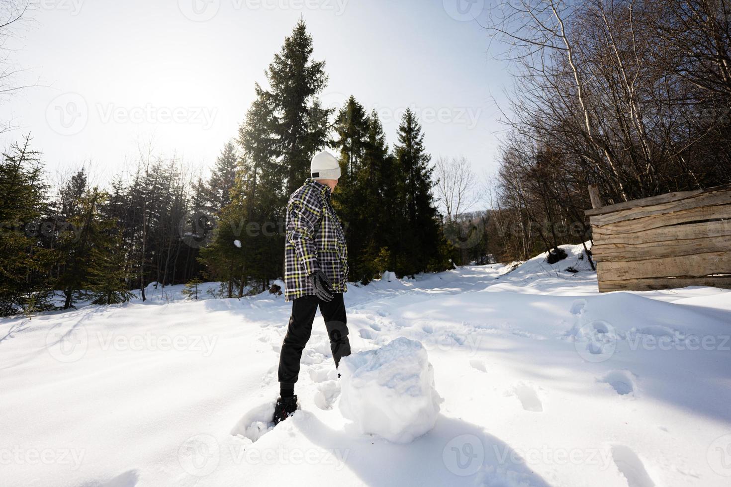 Boy sculpt snow globe for snowman. Game outdoor in winter with snow in mountains. photo