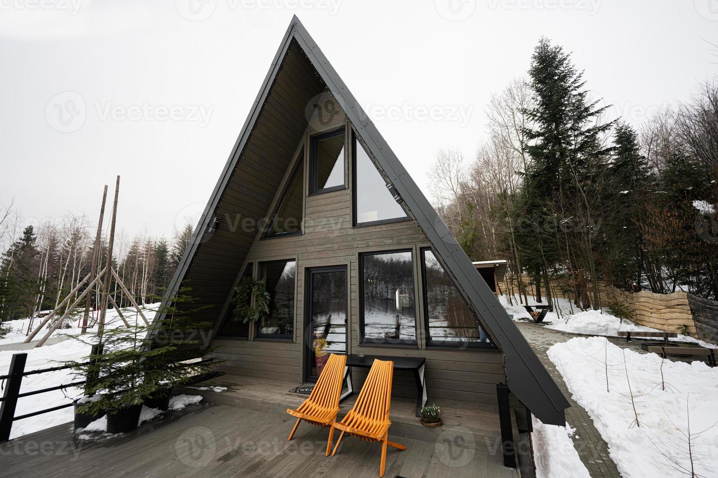 Terrace of wooden triangle country tiny cabin house in mountains and two chairs. photo