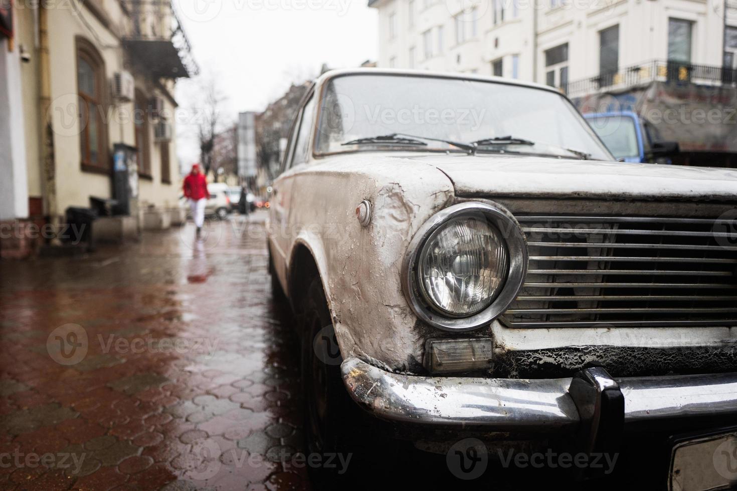 Old vintage car headlight in rain city street. photo