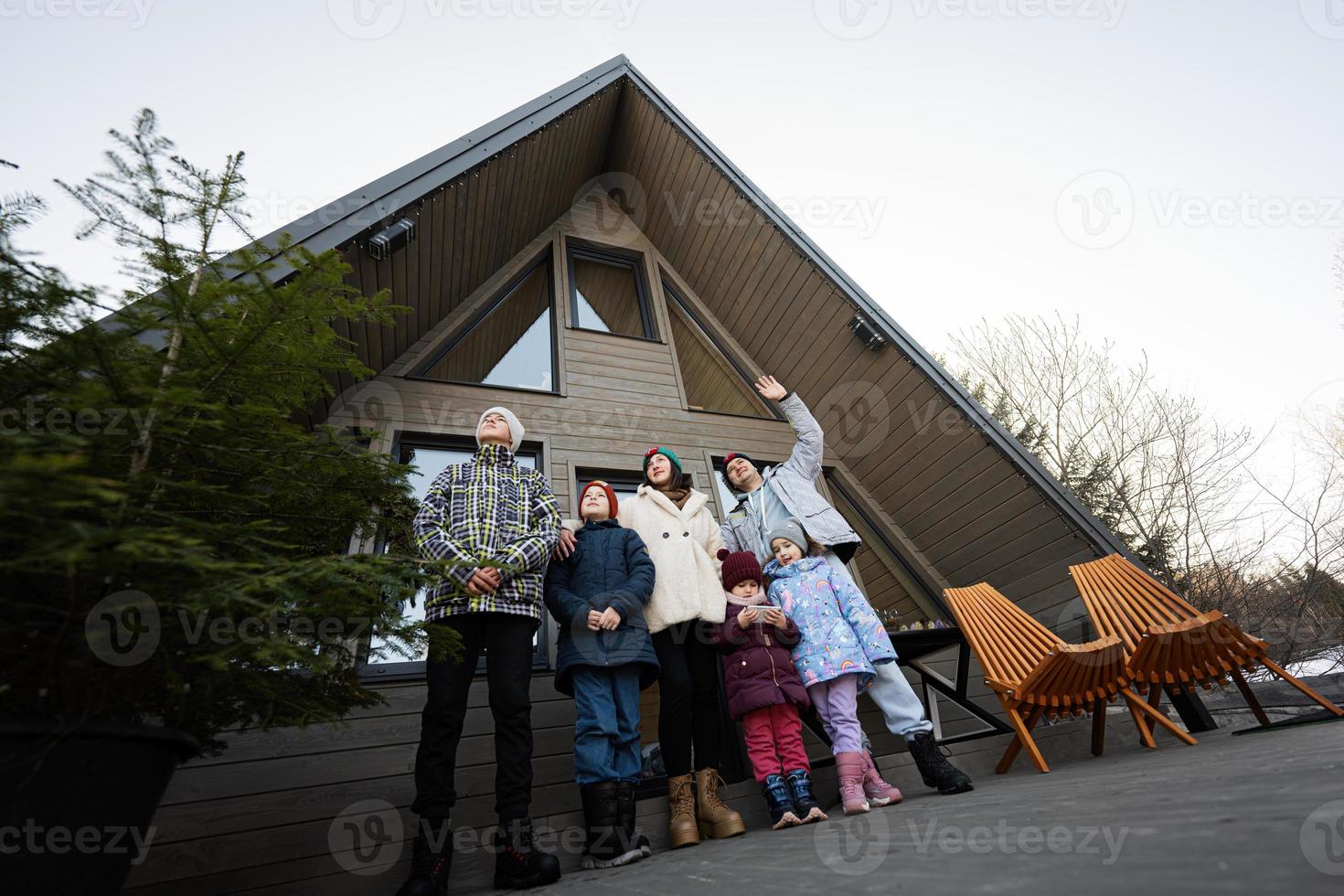 grande familia con cuatro niños en terraza apagado cuadrícula minúsculo casa en el montañas. foto