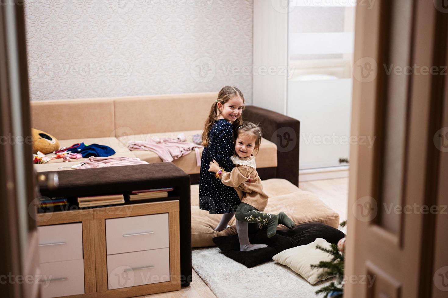 Two sisters at home on the sofa hugging tightly together. photo