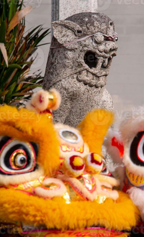 Old lion statue with front lion dance in front of temple photo