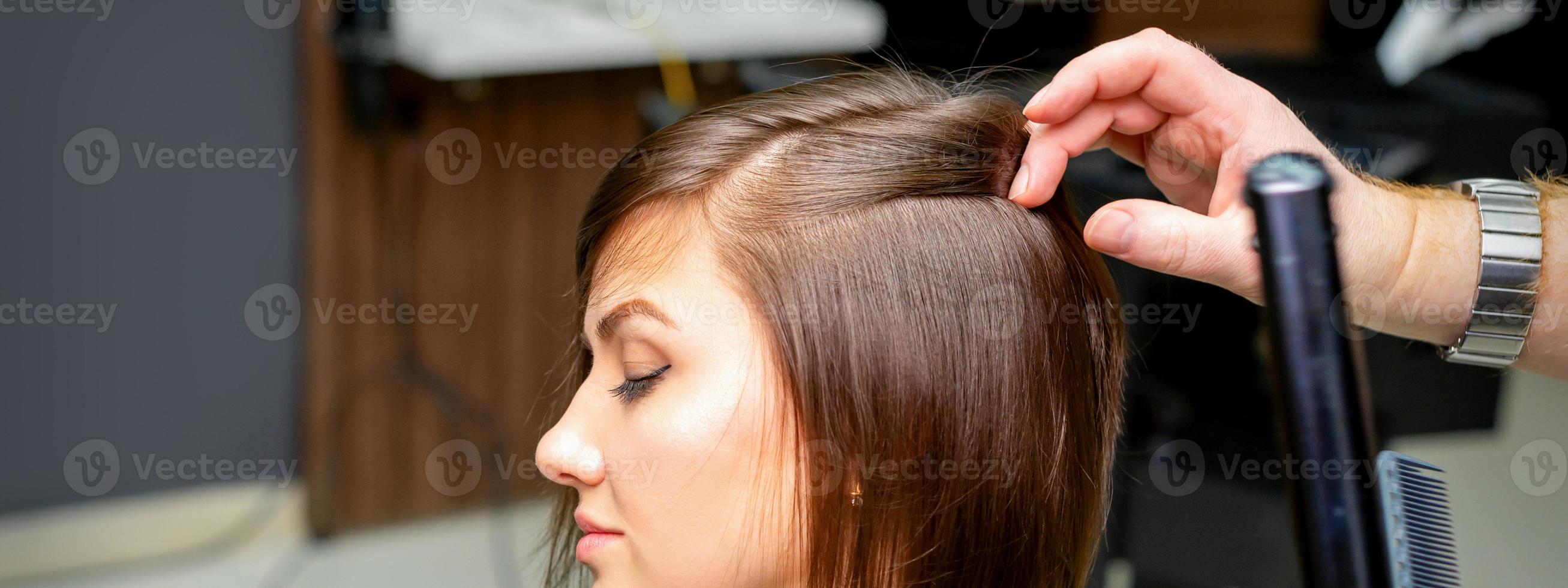 Hairdresser is straightening the hair photo