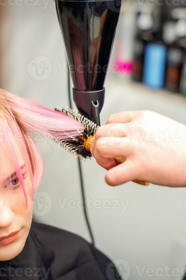 Hairdresser dries pink hair of woman photo