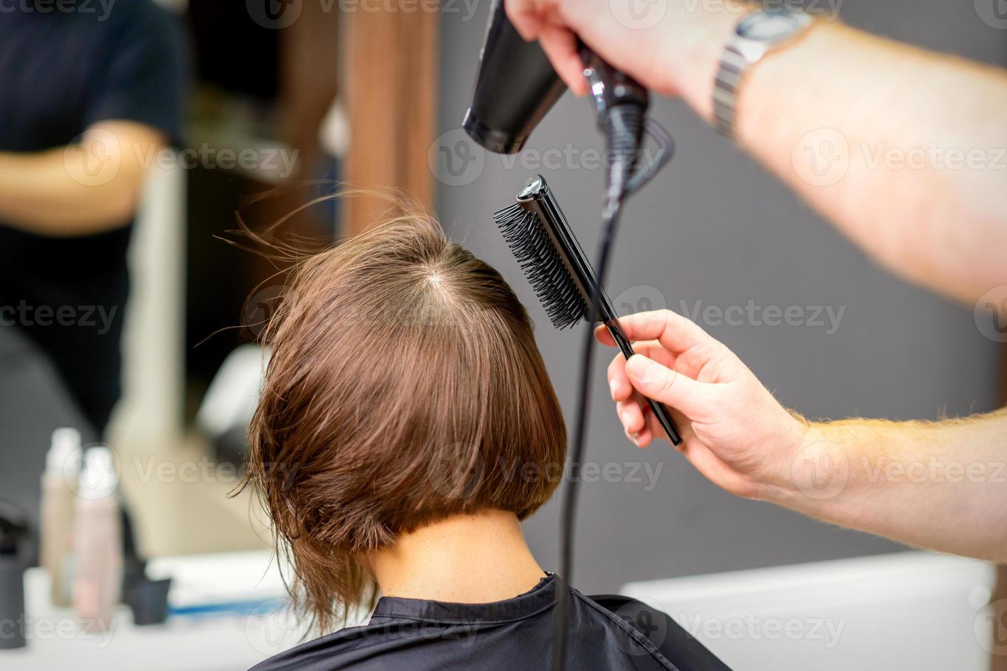 Hairdresser dries brown hair of woman photo