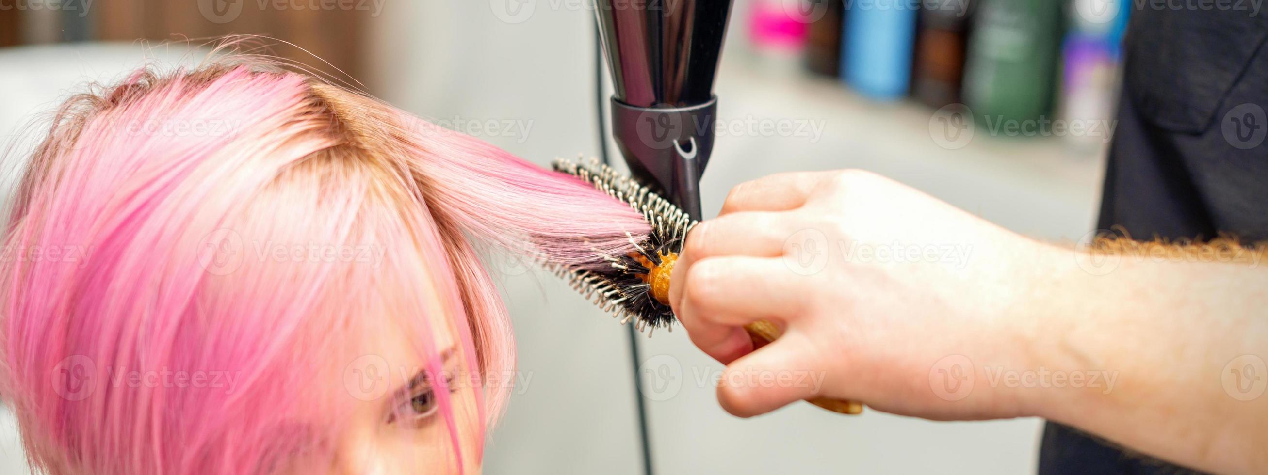 Hairdresser dries pink hair of woman photo