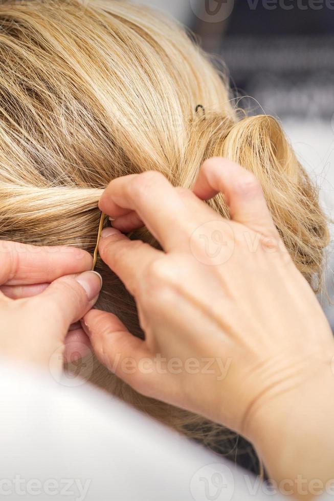 Hairdresser stabs hair with hairpin photo