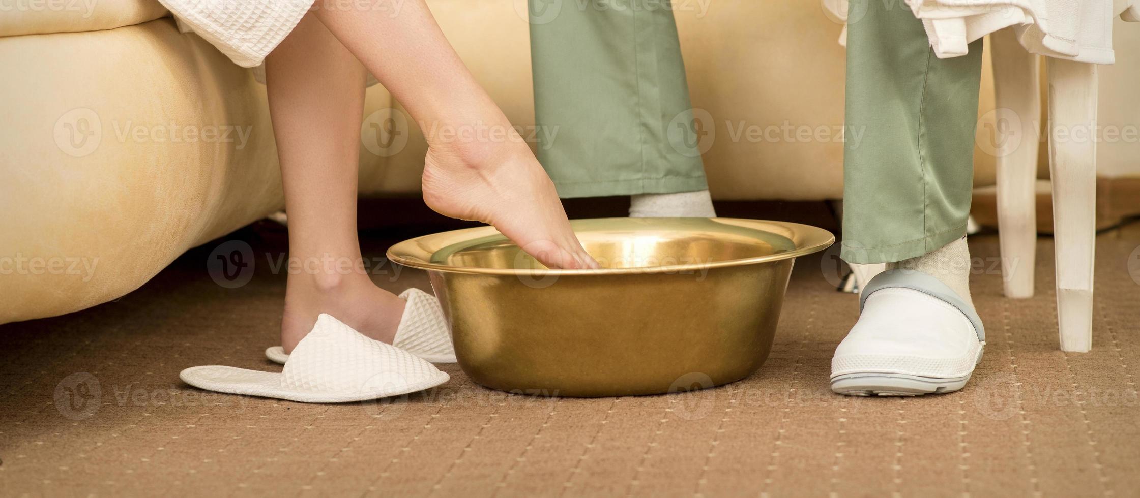 Woman is dipping feet in bowl photo