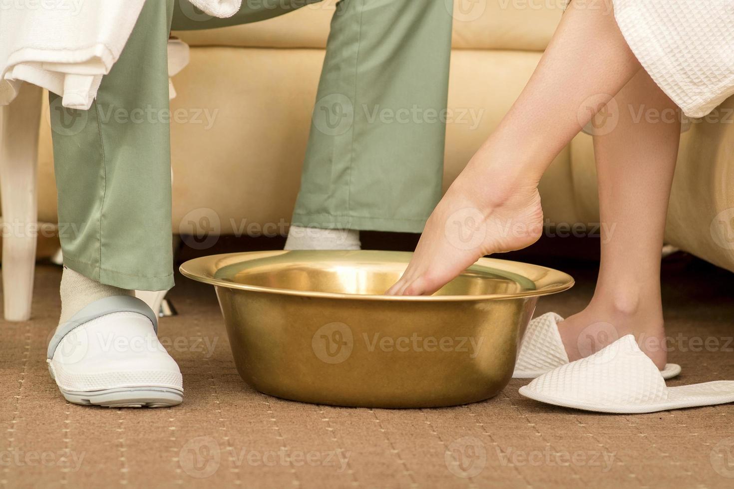 Woman is dipping feet in bowl photo
