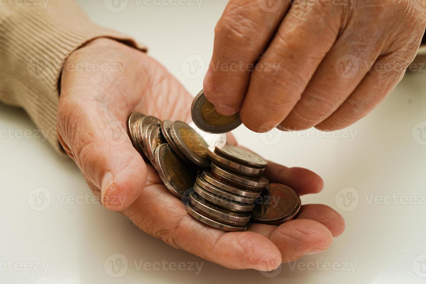 Retired elderly woman counting coins money and worry about monthly expenses and treatment fee payment. photo