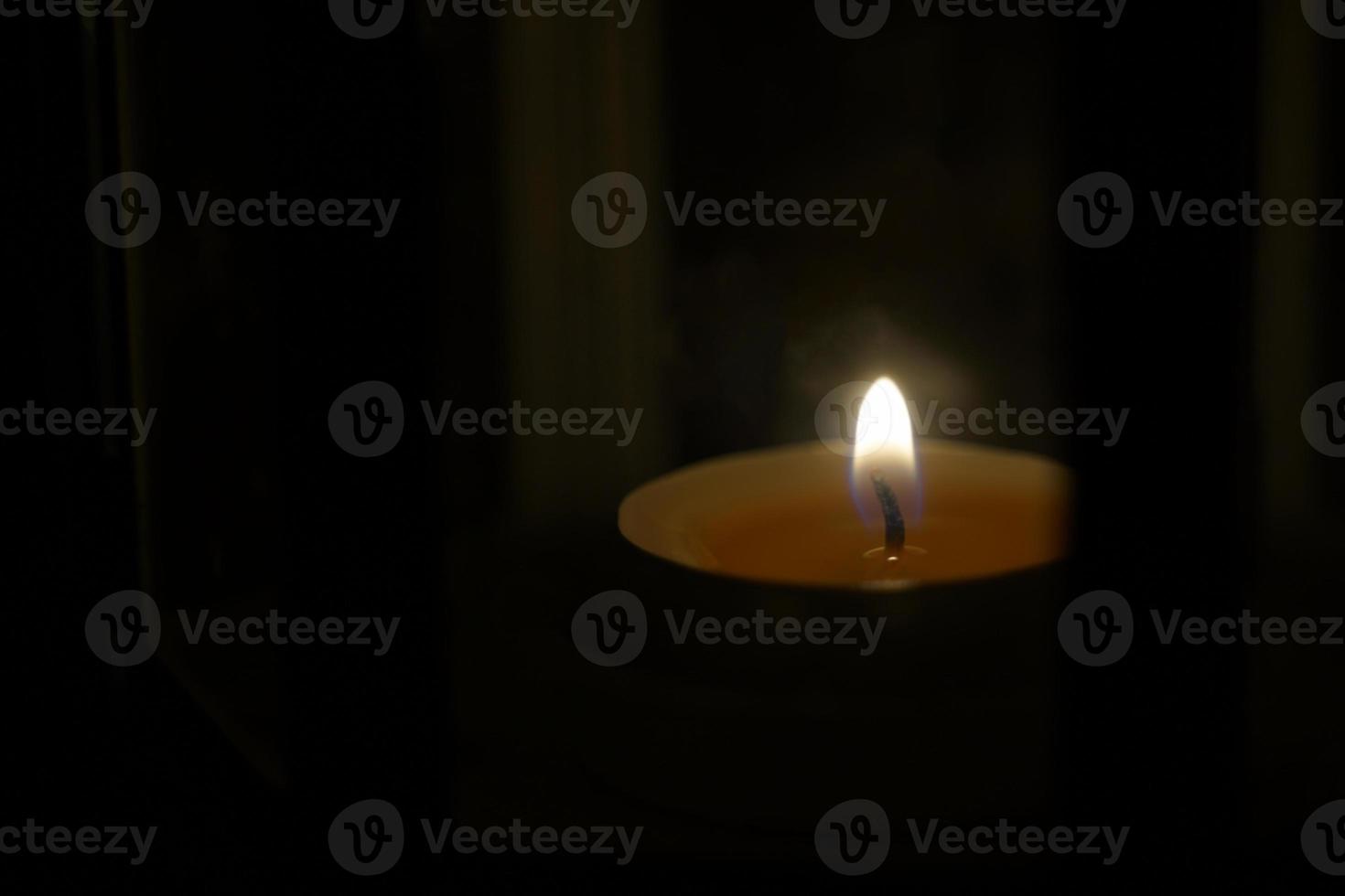 candlelight in lantern on black background of darkness at night. The burning of candles symbolizes worship, hope, encouragement, love, remembrance and relaxation. Soft and selective focus. photo