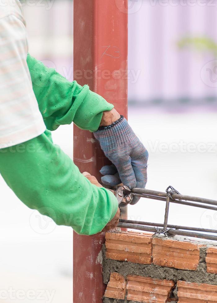 Workers using steel wire and pincers rebar before concrete is poured photo