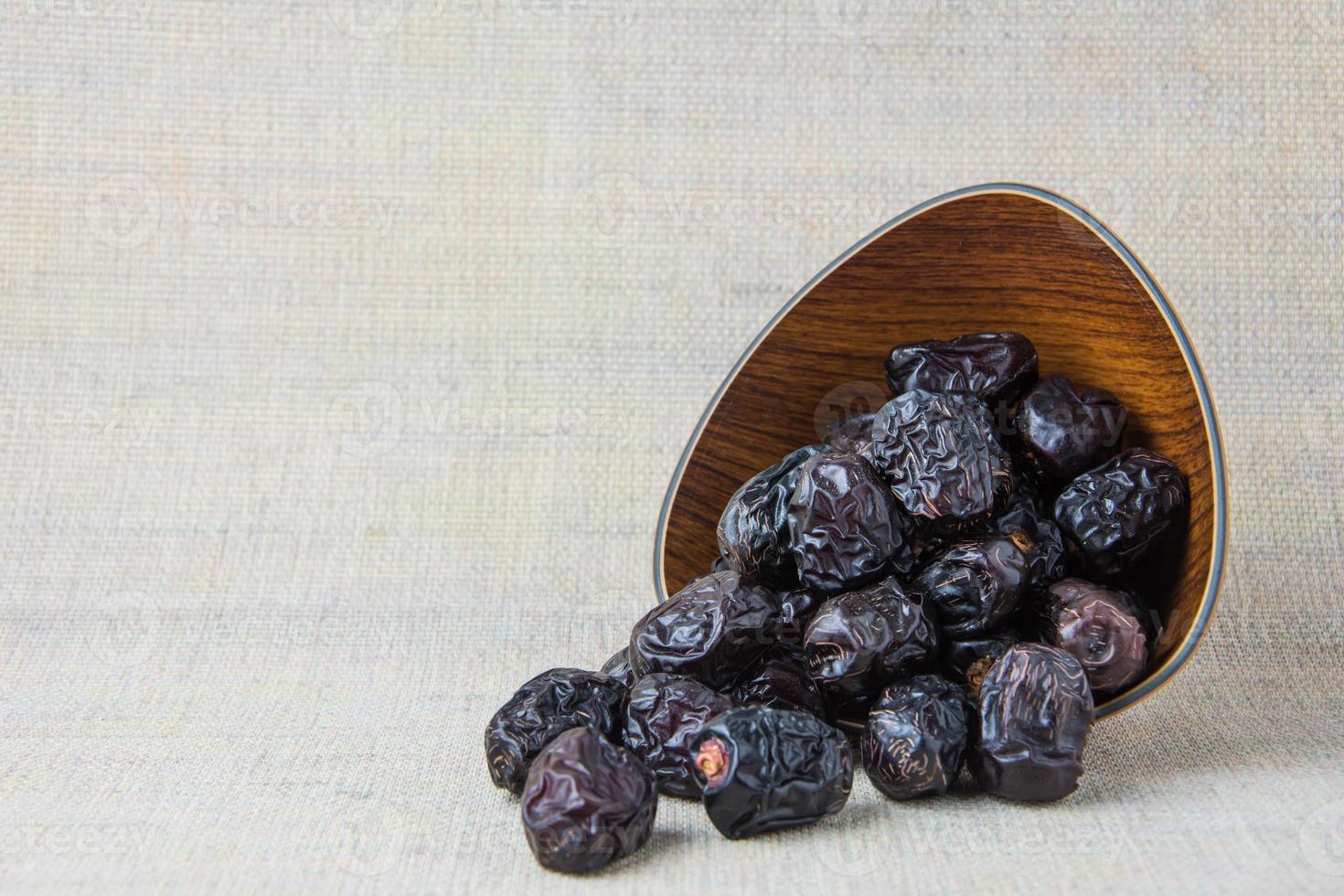 Delicious ajwa dates kurma nabi, or sweet dried dates on a plate, with some falling from the plate, as a meal for breaking the fast, ramadan kareem, empty space, copy space. photo