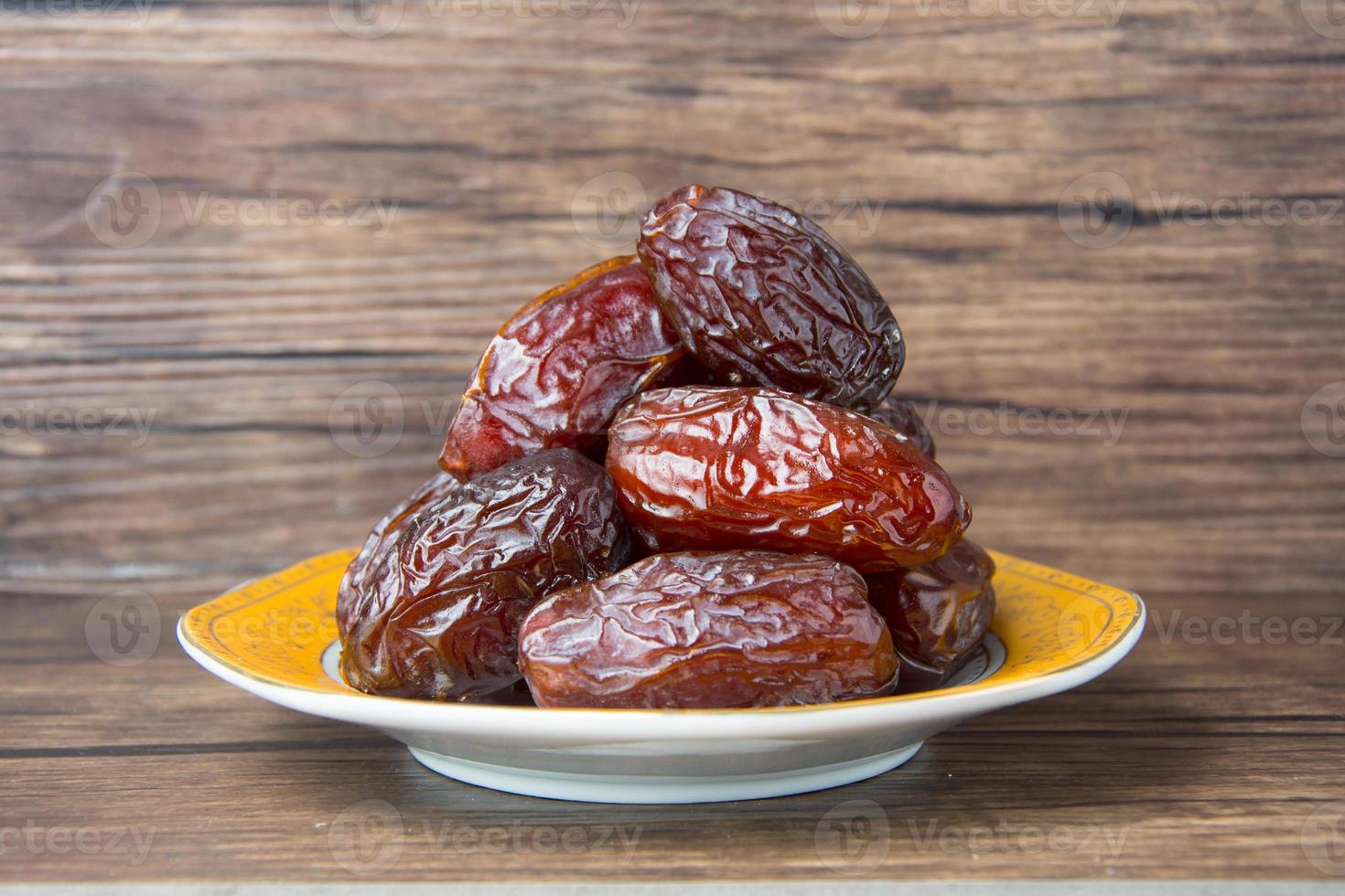 Delicious medjool dates or sweet dried dates on a plate, with some falling from the plate, as a meal for breaking the fast, ramadan kareem, empty space, copy space photo