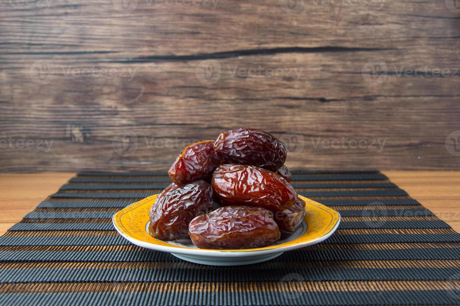 Delicious medjool dates kurma or sweet dried dates on a plate, with some falling from the plate, as a meal for breaking the fast, ramadan kareem, empty space, copy space. photo