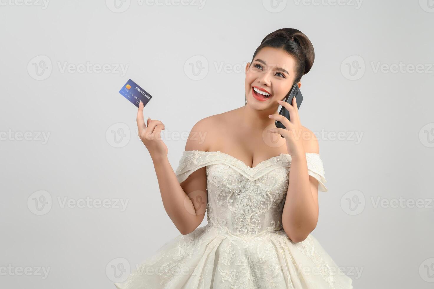 Young asian beautiful bride posting with credit card and smartphone in hand photo