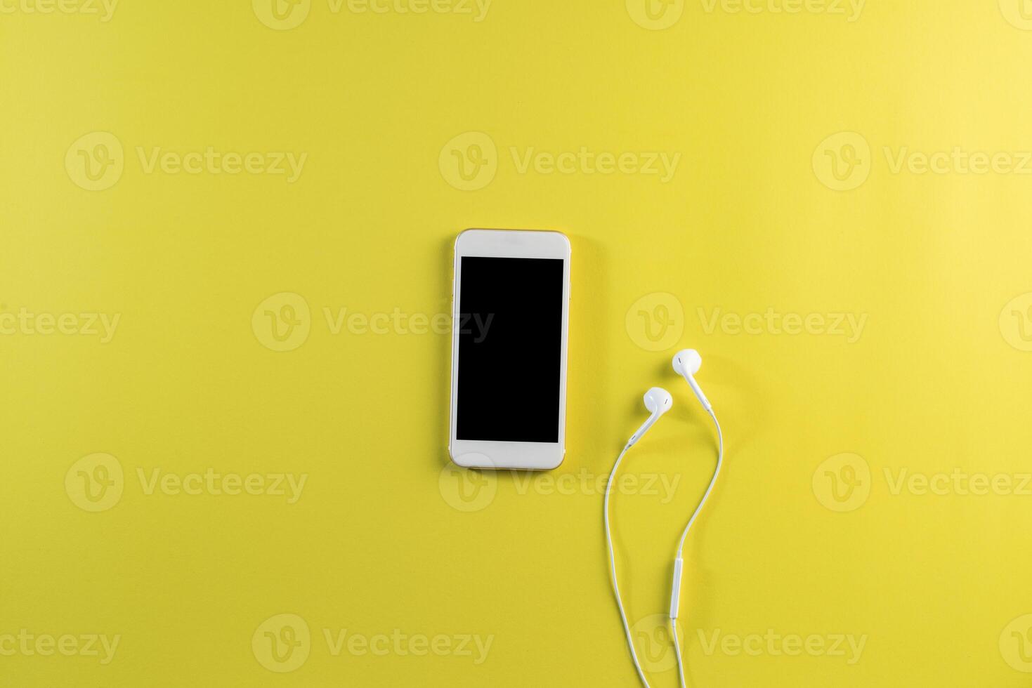 Top view cell phone and earphone on white desk photo
