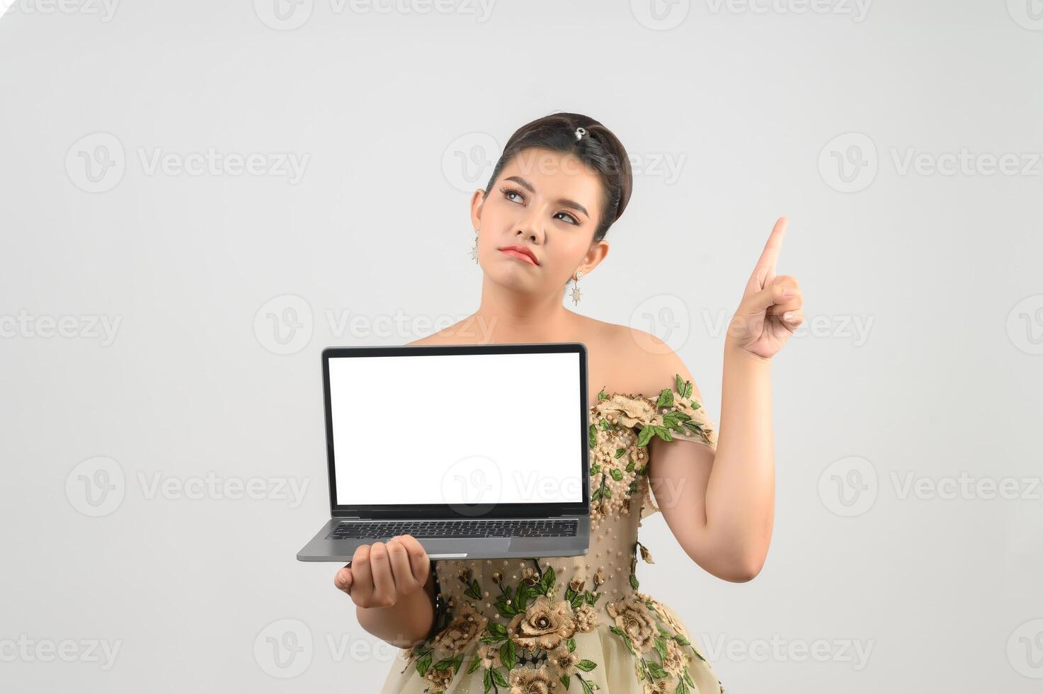 Young asian beautiful bride pose with mock up laptop computer in hand photo