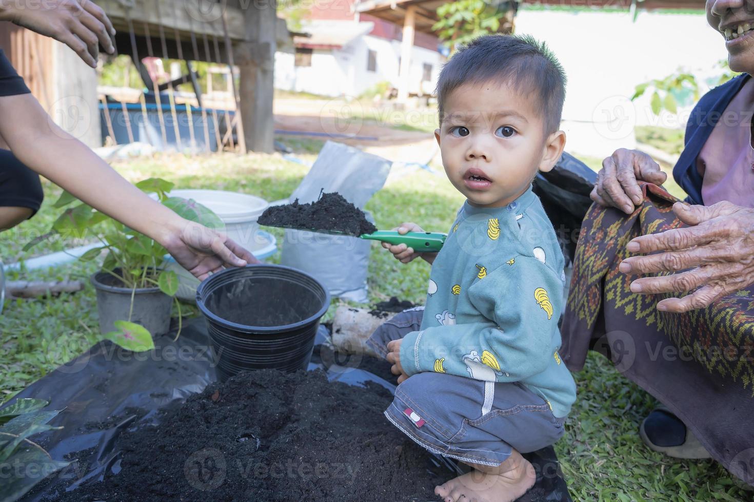 Toddler son and mother teaching little son preparing the soil to plant in a garden, mother and son relationship. Mommy's little helper. Gardening. Leisure activities family concept photo