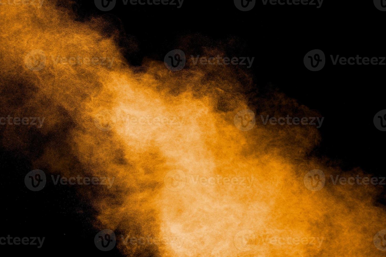 Abstract explosion of orange dust on black background.Freeze motion of orange powder burst. photo