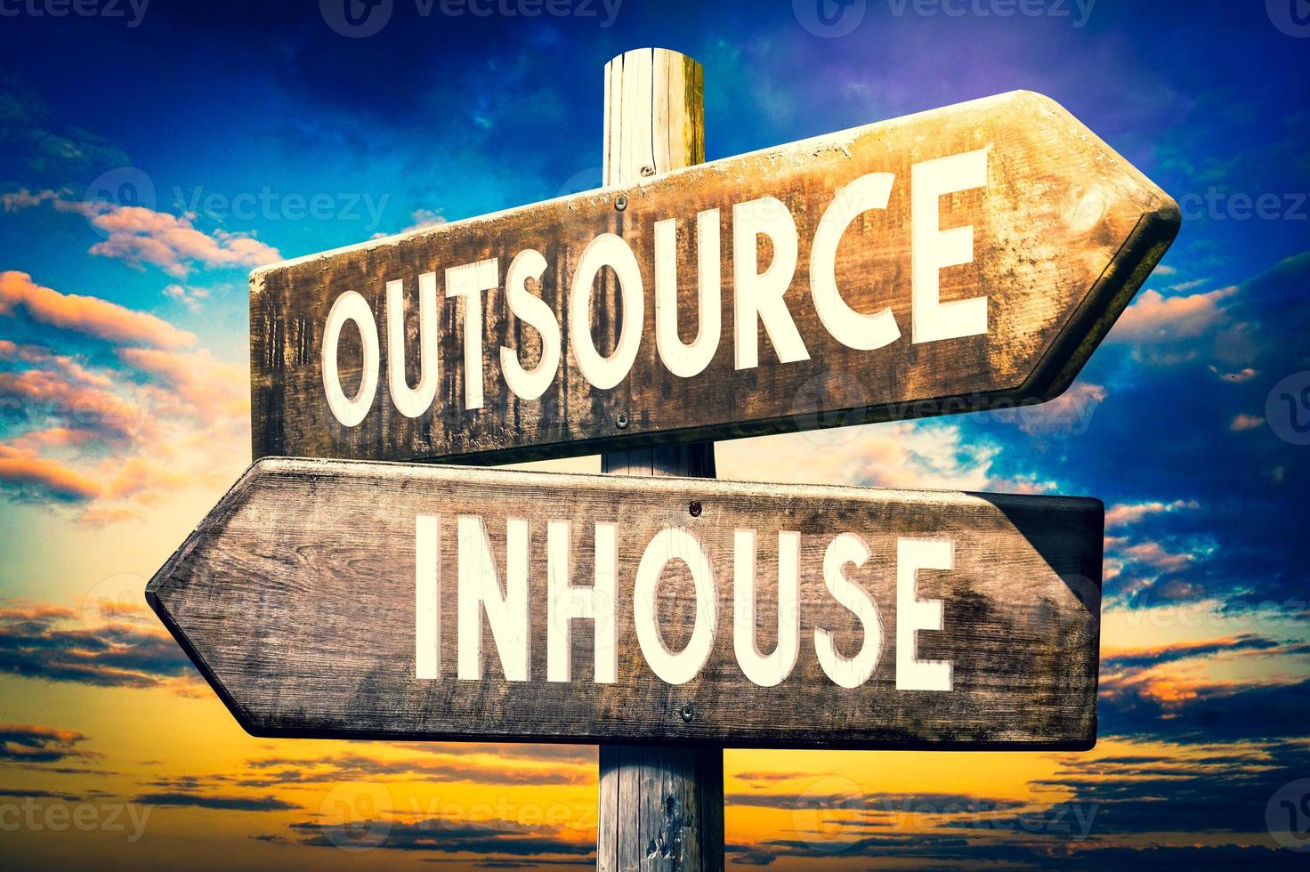 Outsource, Inhouse - Wooden Signpost with Two Arrows, Sunset Sky in Background photo