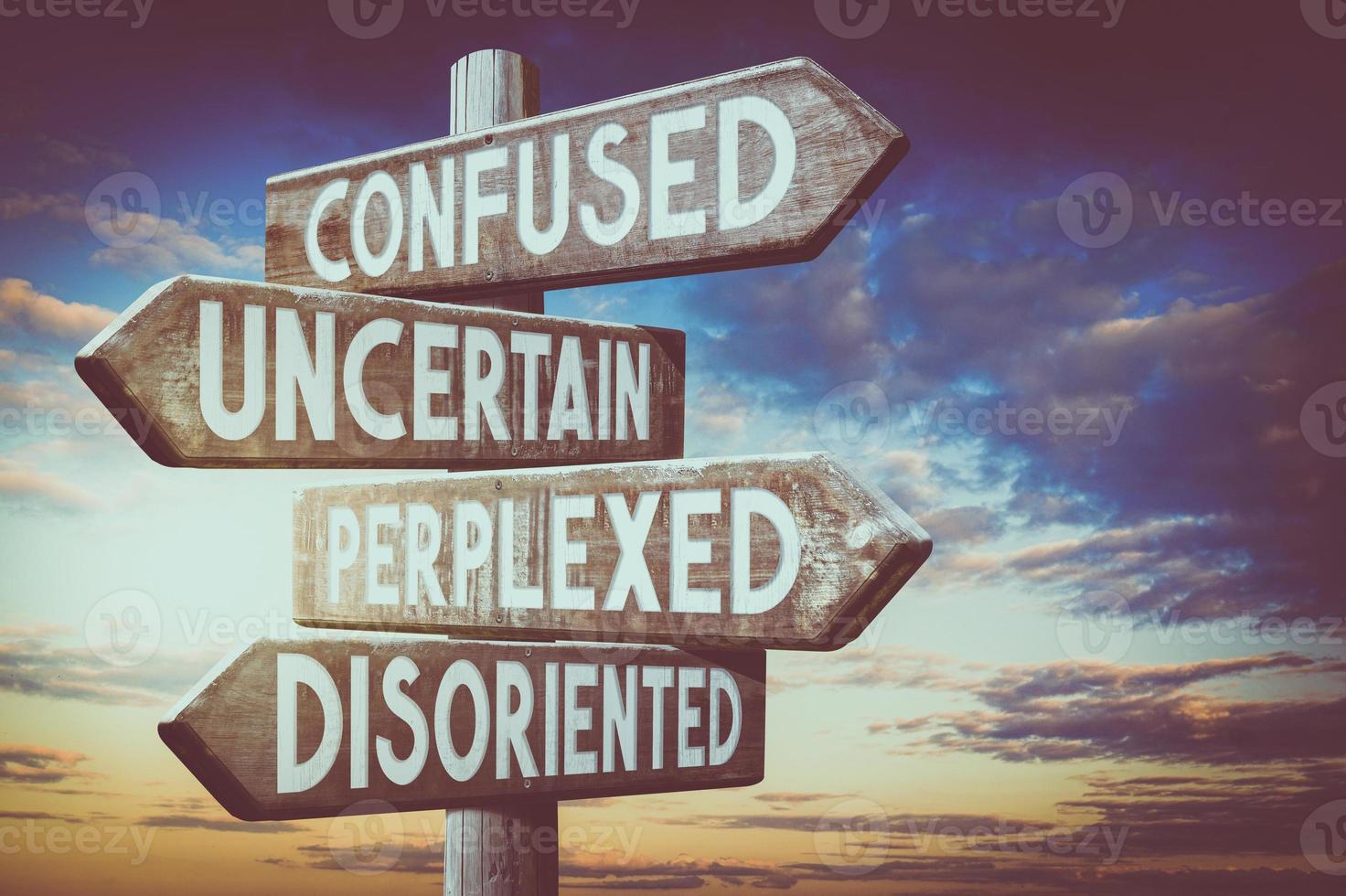 Confused, Uncertain, Perplexed, Disoriented - Wooden Signpost with Four Arrows, Sunset Sky in Background photo
