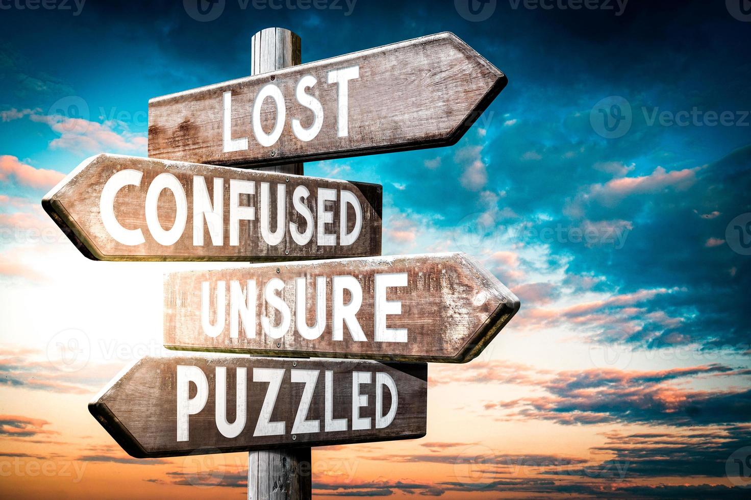 Lost, Confused, Unsure, Puzzled - Wooden Signpost with Four Arrows, Sunset Sky in Background photo
