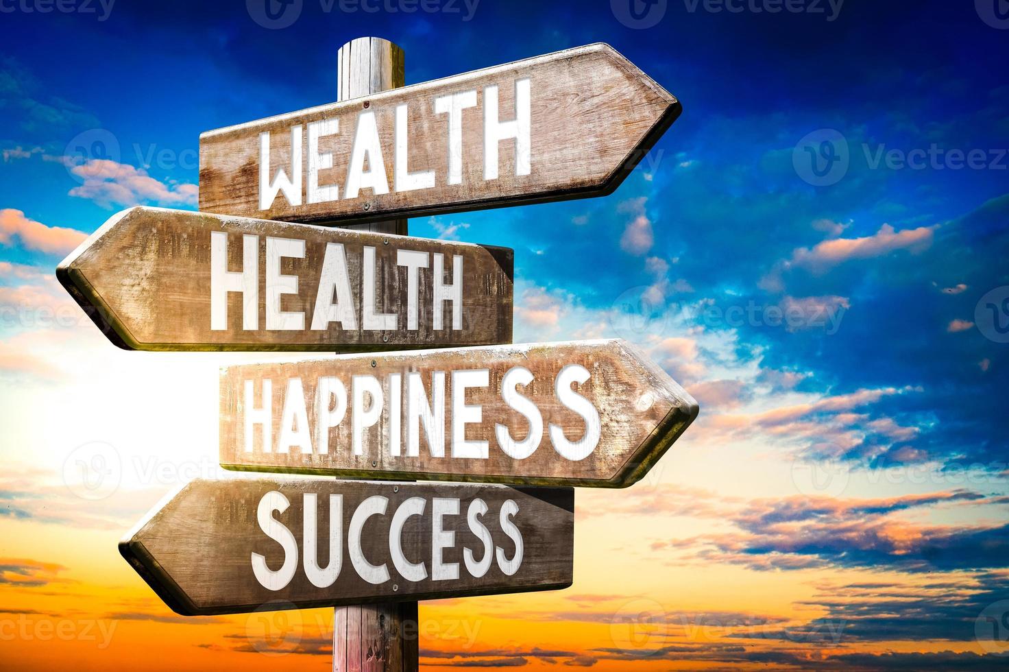 Wealth, Health, Happiness, Success - Wooden Signpost with Four Arrows, Sunset Sky in Background photo