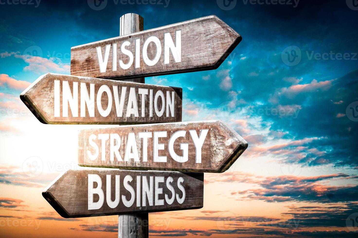 Vision, Innovation, Strategy, Business - Wooden Signpost with Four Arrows, Sunset Sky in Background photo