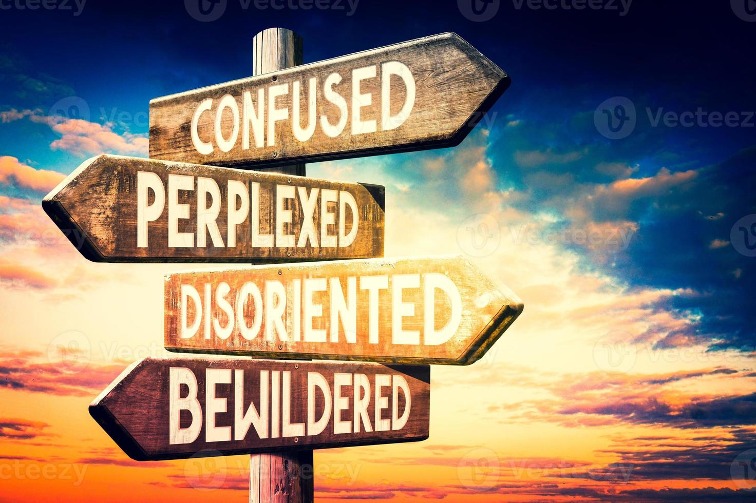 Confused, Perplexed, Disoriented, Bewildered - Wooden Signpost with Four Arrows, Sunset Sky in Background photo