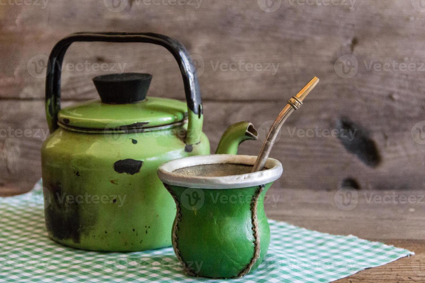 mate and kettle, traditional Argentine yerba mate infusion, on rustic wooden background photo