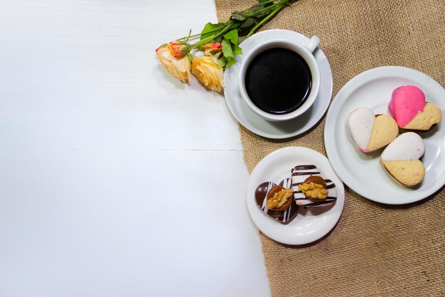 romantic flowers with coffee and sweet treats on the table photo