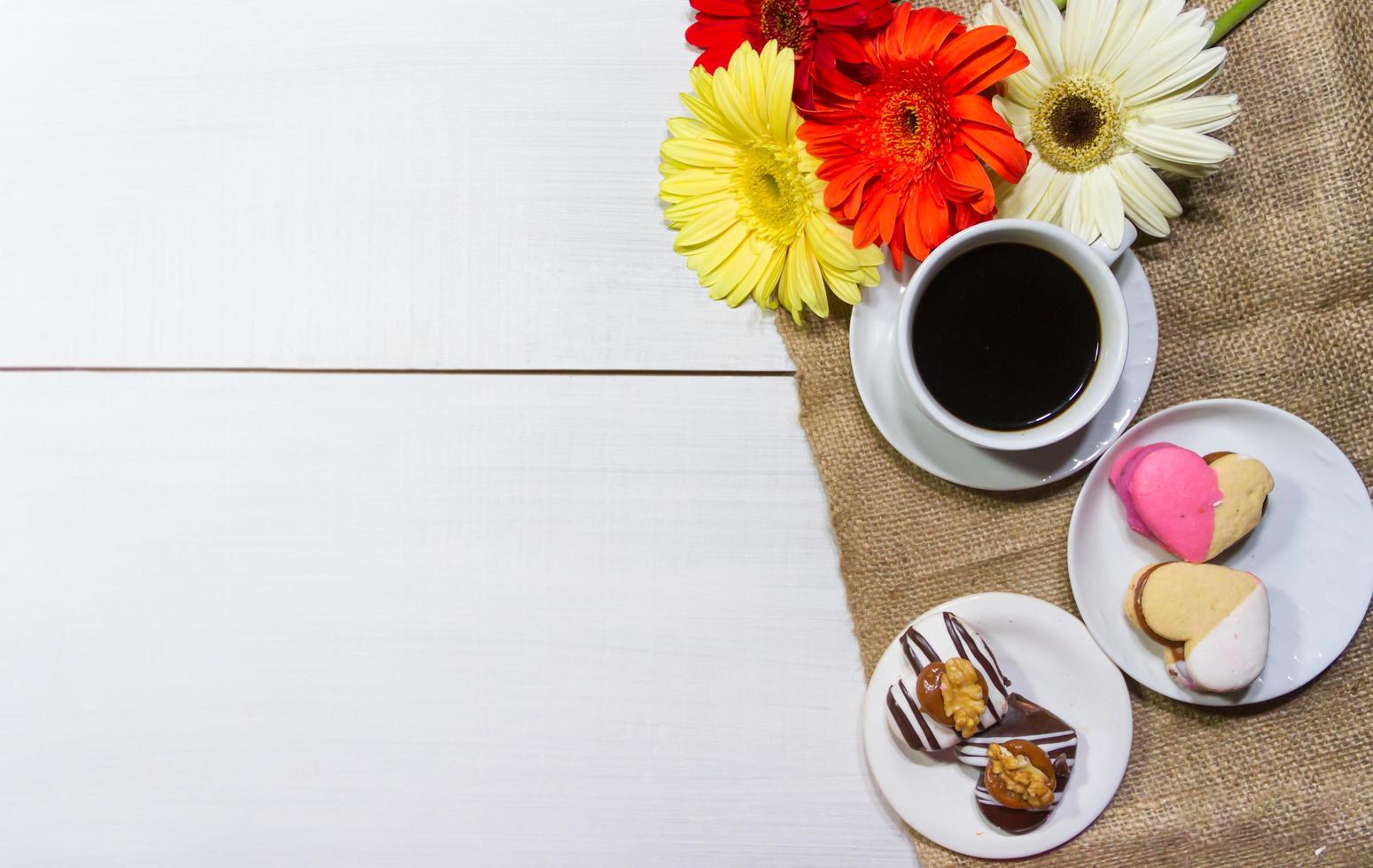 romántico flores con café y dulce trata en el mesa foto