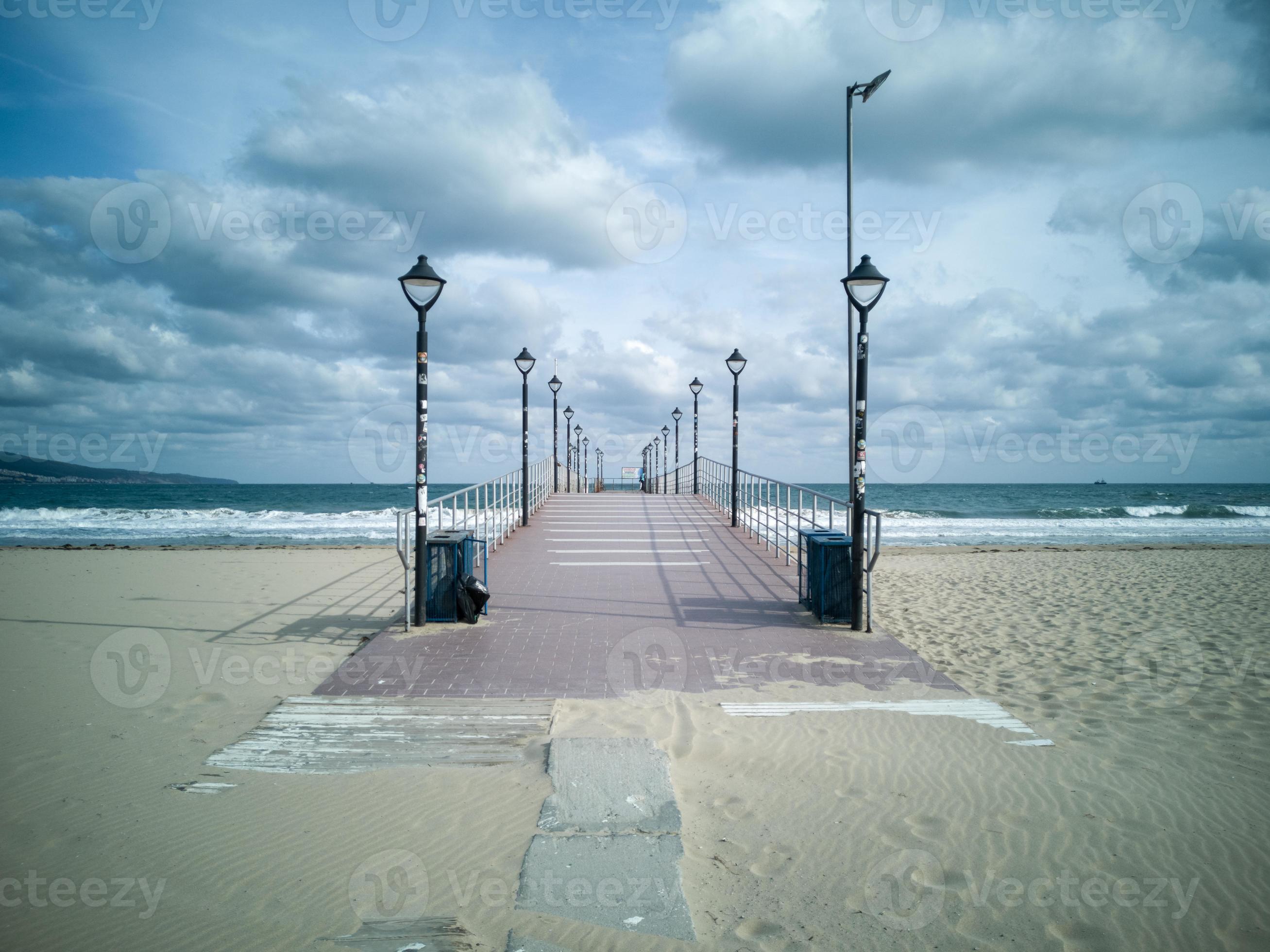 https://static.vecteezy.com/system/resources/previews/021/681/706/large_2x/a-wooden-pier-for-pleasure-and-fishing-boats-against-the-backdrop-of-a-stormy-blue-sea-and-clouds-photo.jpg