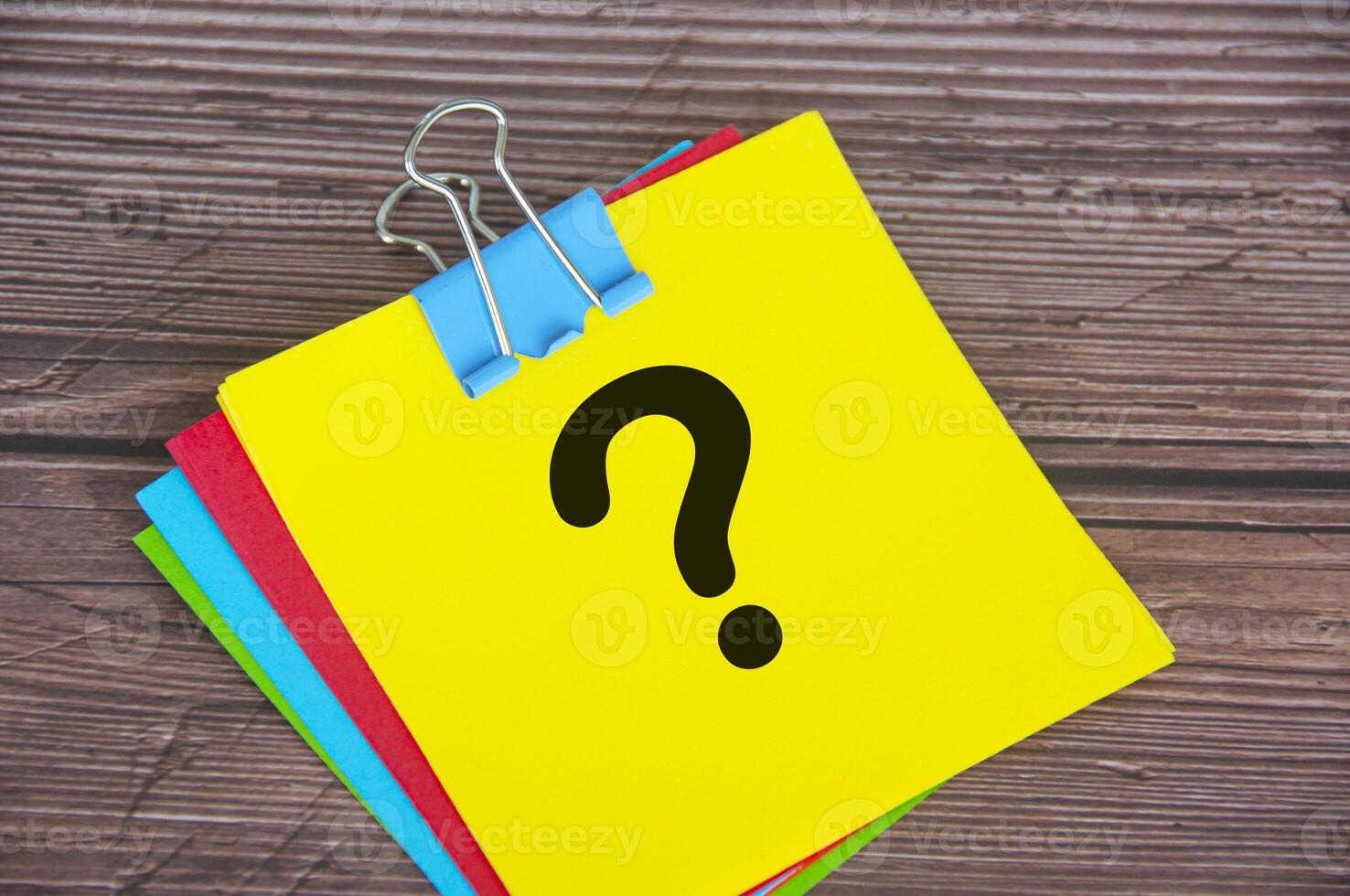 Question mark on yellow notepad with wooden desk background. Motivational concept. photo