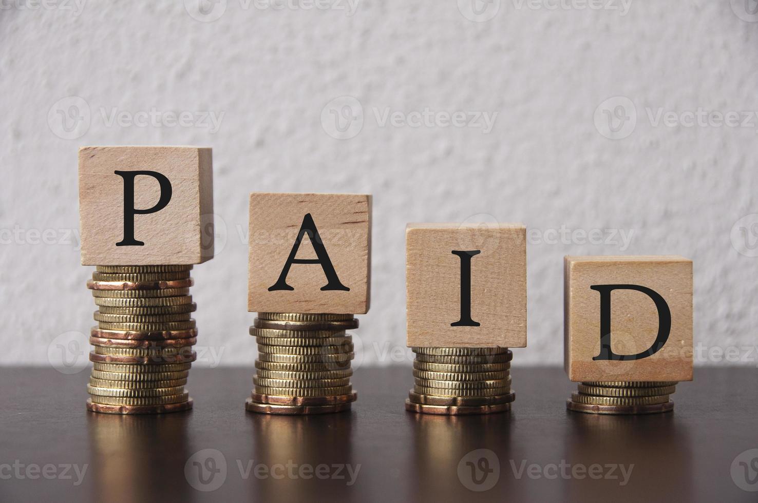 Coins Stack with paid text on wooden blocks - Financial Concept photo