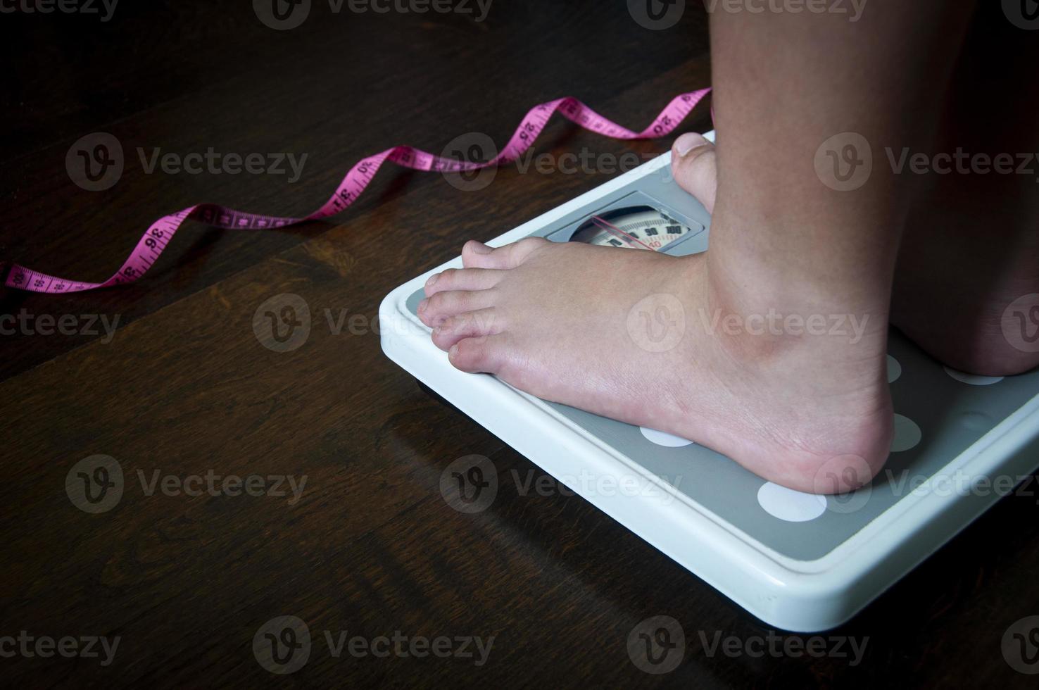 Side view of measuring tape and feet on weight scale . Weight loss concept. photo