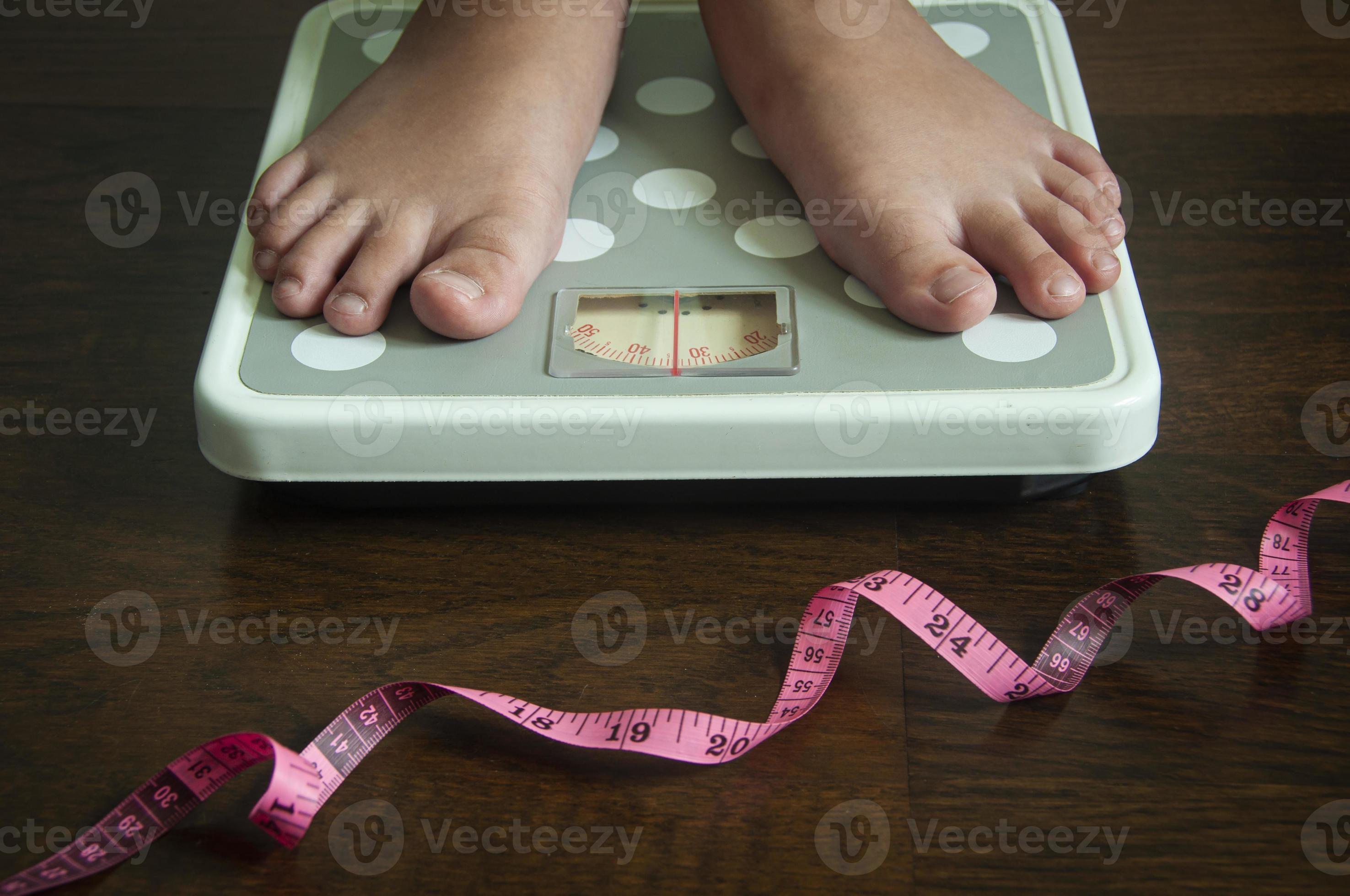 Straight view of measuring tape and feet on weight scale . Weight loss