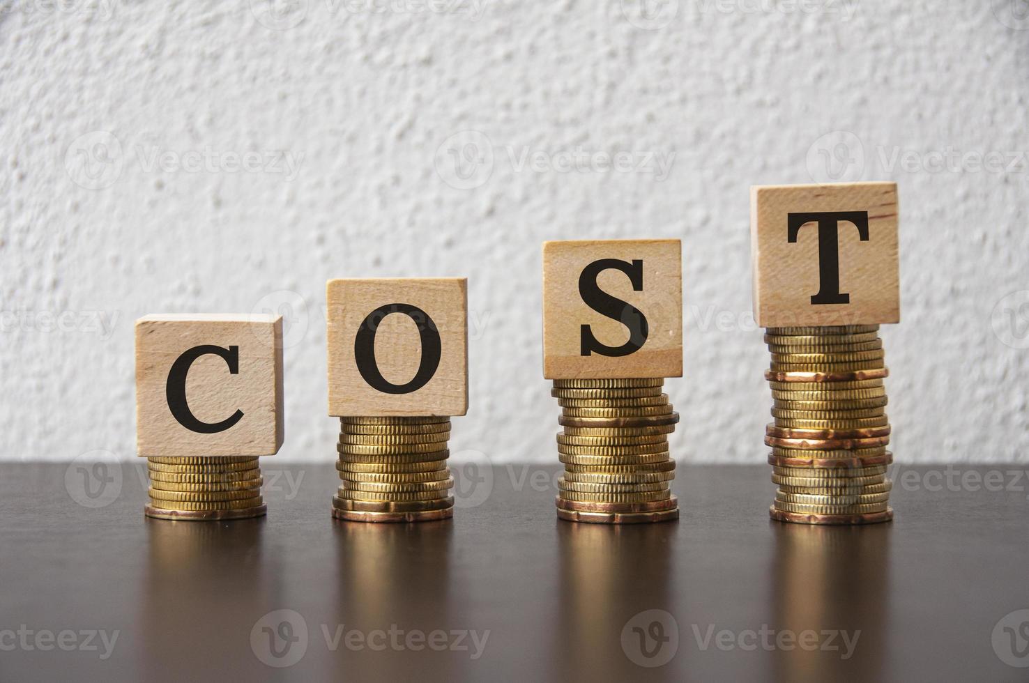 Coins stack with Cost text on wooden blocks - Financial Concept photo