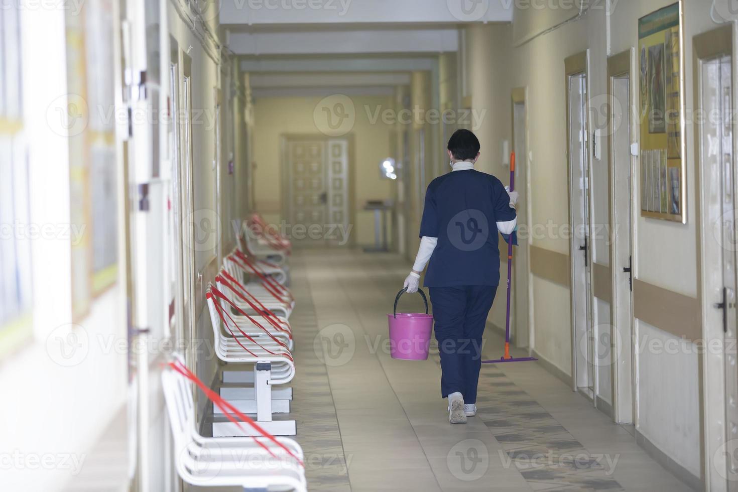 A cleaning lady is walking along the corridor of a hospital or clinic. photo