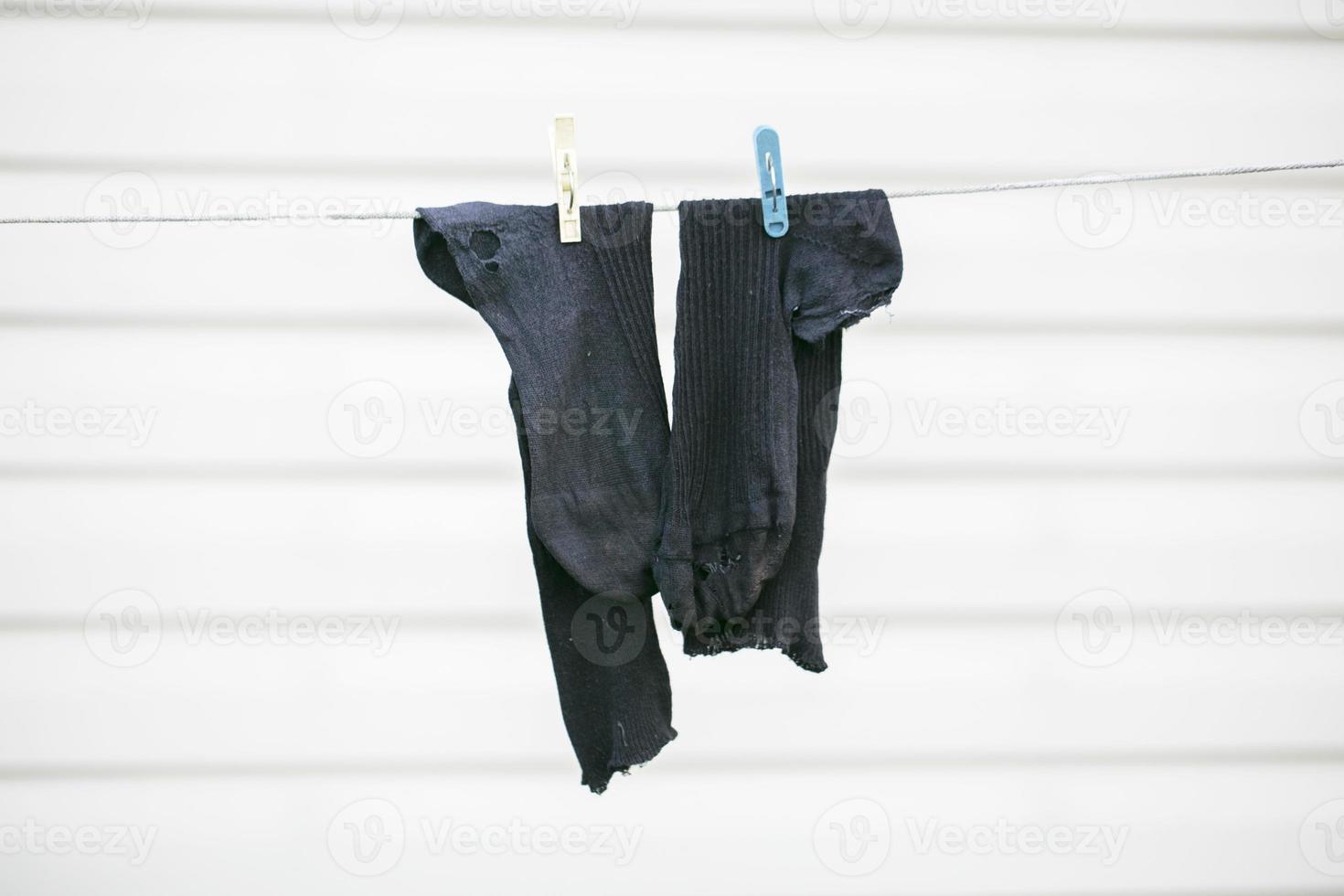 Dry old torn black socks on a rope. Poverty concept. photo