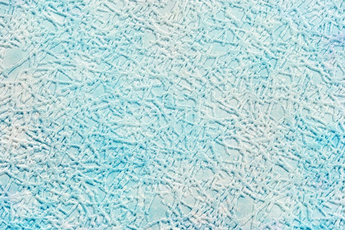 On a pale blue paper background, textured strokes imitating hoarfrost or a pattern of hoarfrost on glass. photo
